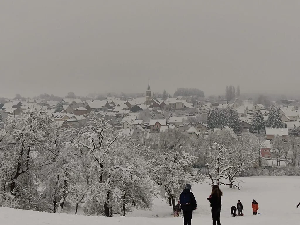 Muespach-le-Haut sous la neige en hiver avec des enfants qui font de la luge